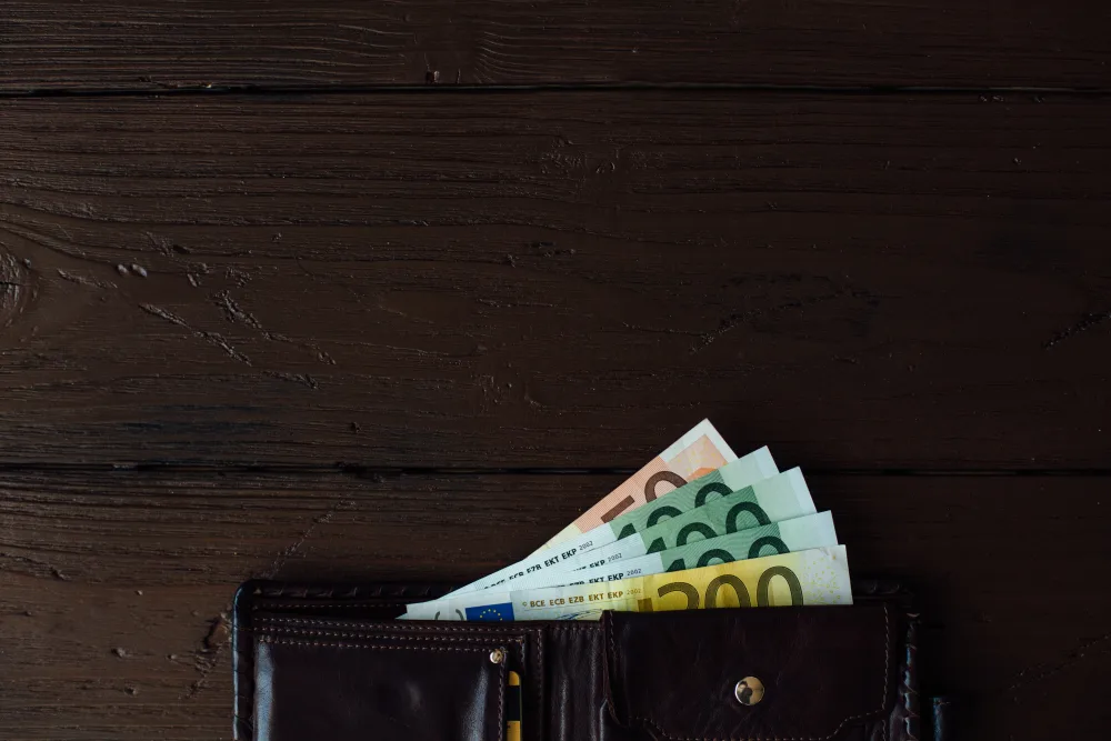 Geldbeutel mit Euro-Banknoten auf dunklem Holz