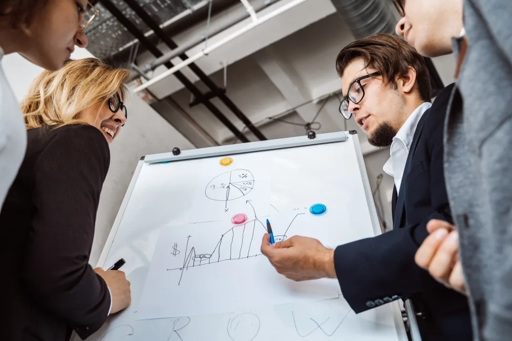 Menschen diskutieren vor einem Whiteboard mit handgezeichnetem Diagramm