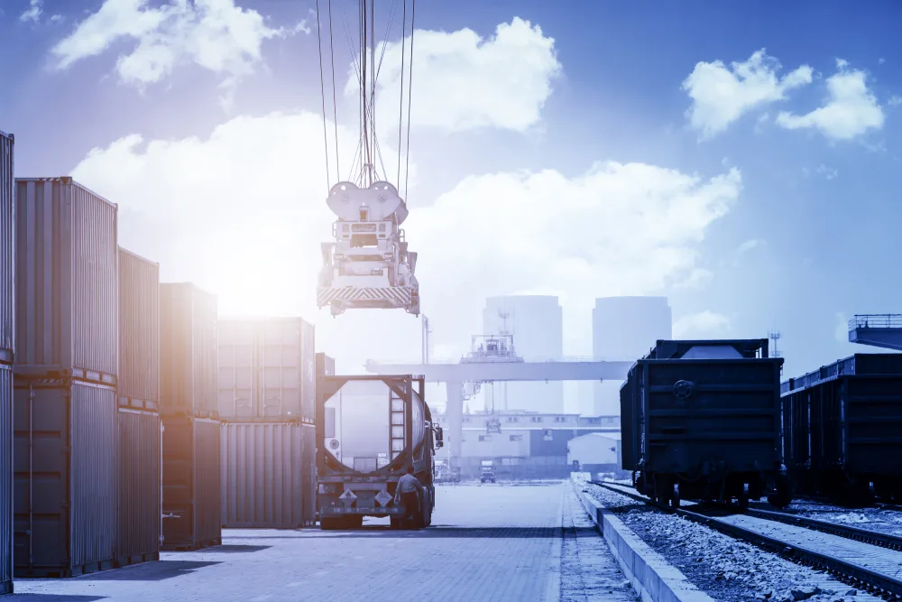 Container und Güterwaggons im Gegenlicht an einem Umschlagplatz