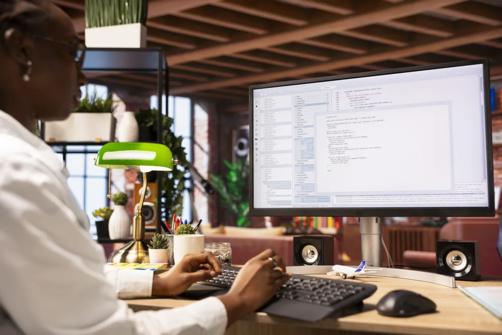 Person schreibt Code am Monitor neben einer grünen Lampe